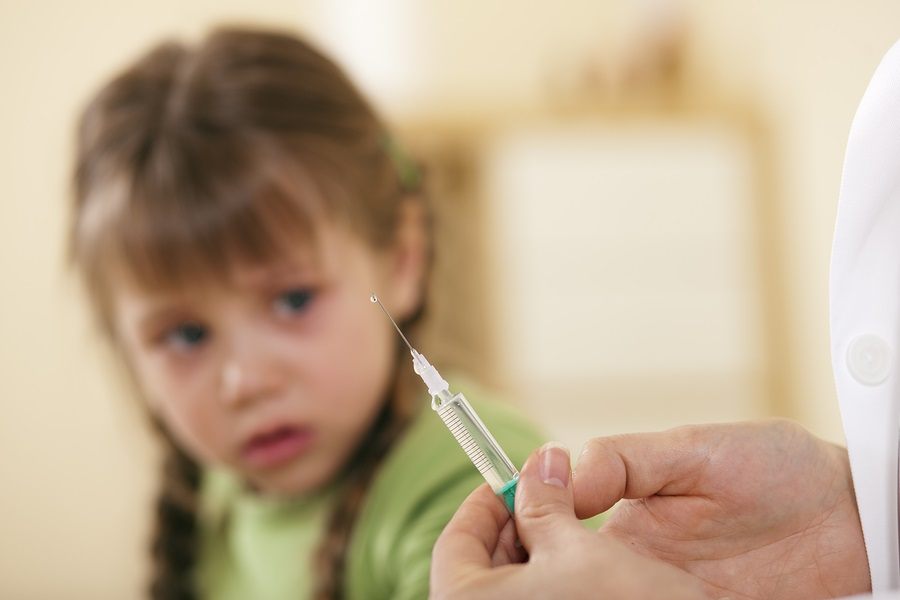 Pediatrician doctor applying syringe to child