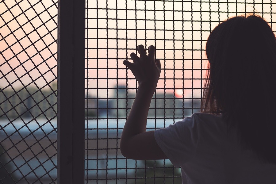 Woman's hand grabs the fence, concept of imprisonment, social issue violence, and prostitution issue