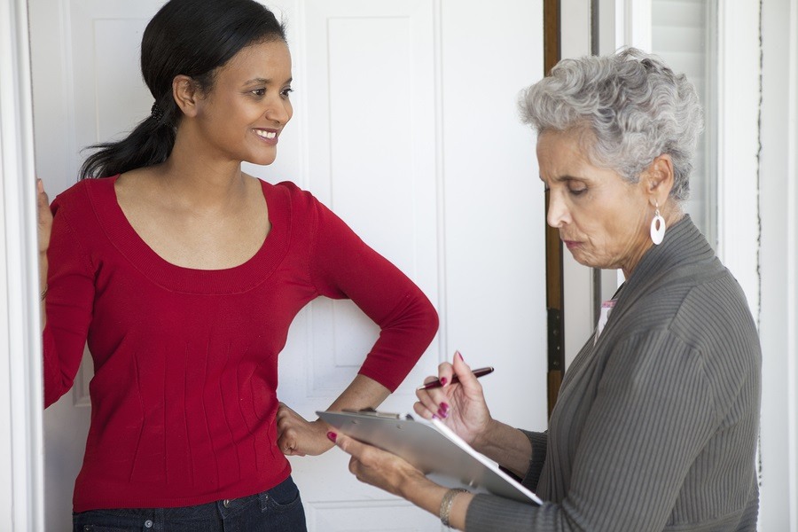 Black woman greeting a solicitor at her front door photo