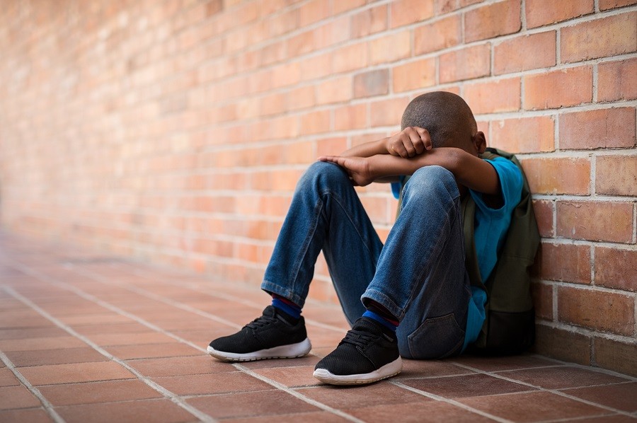 Young boy sitting alone with sad feeling at school. 