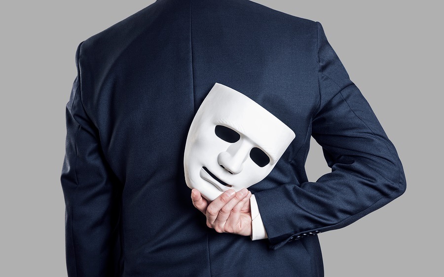 Business fraud concept. Businessman hide the mask in hand behind